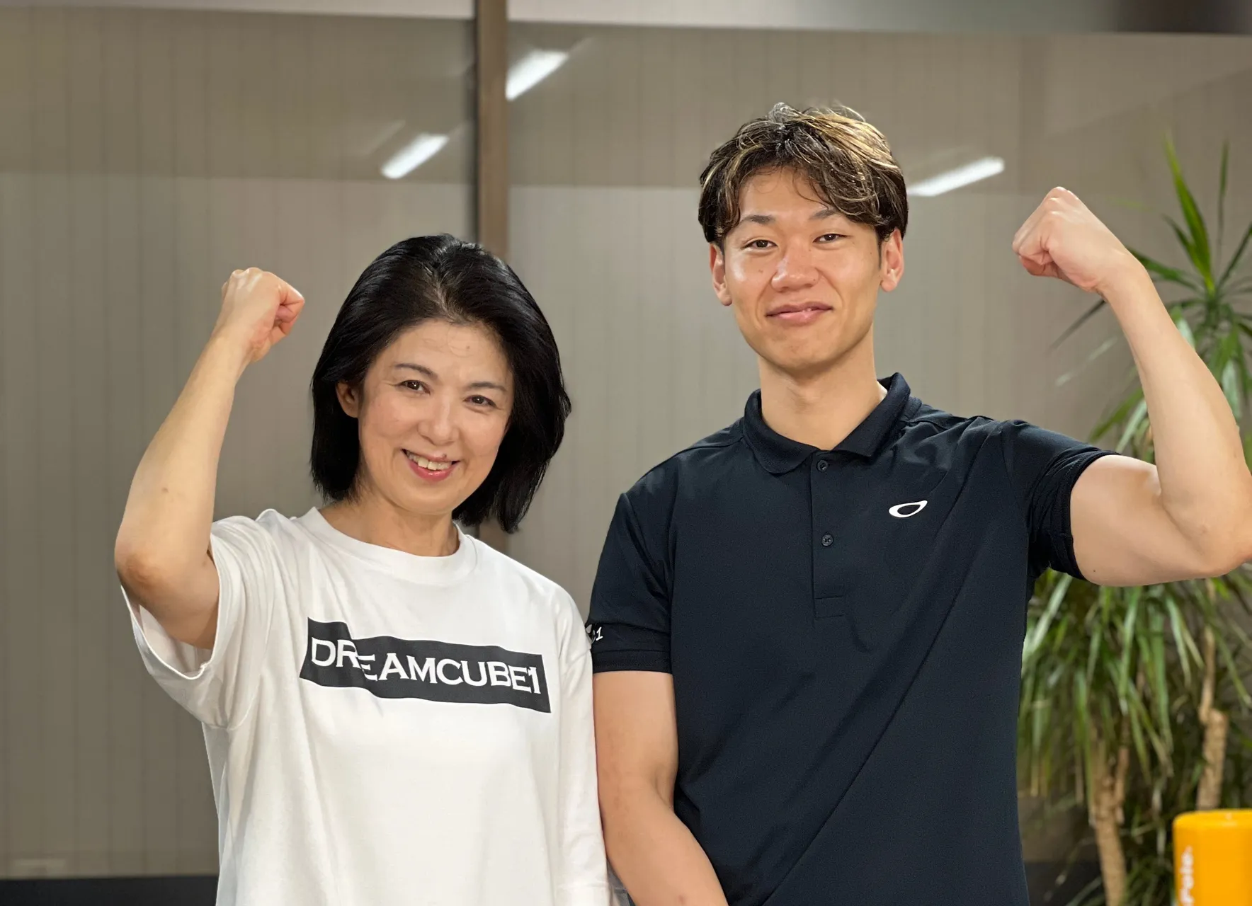 力こぶポーズで笑顔の女性会員とトレーナー